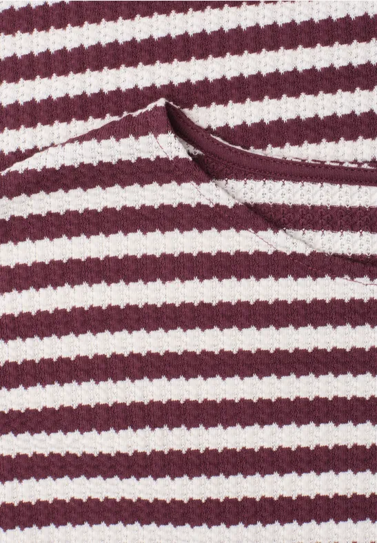 Close-up van een rood-wit gestreept gebreid kledingstuk met een opgestikte zak.