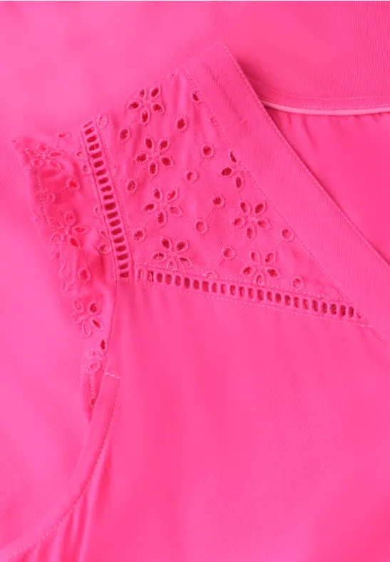 Close-up van een roze mouwloos topje met subtiel geperforeerd borduurwerk bij de schouders.