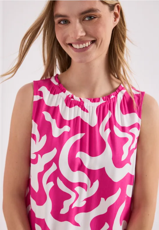 Kind draagt een mouwloze top met roze-wit abstract patroon.