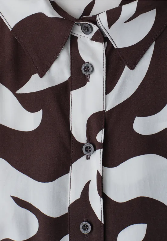 Close-up van een overhemd met een organisch zwart-wit patroon en zwarte knopen.