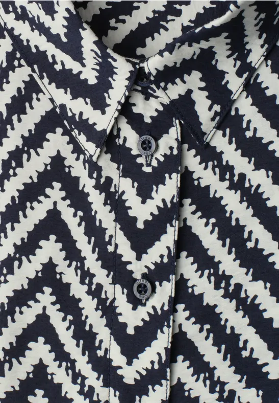 Close-up van een overhemd met zwart-wit zigzagpatroon, knopen en kraag.