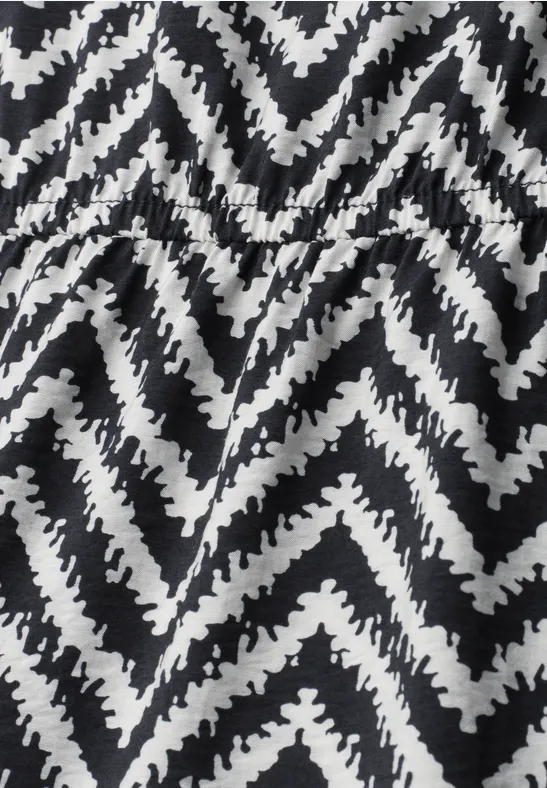 Tissu noir et blanc à motif zigzag cranté avec plis visibles.