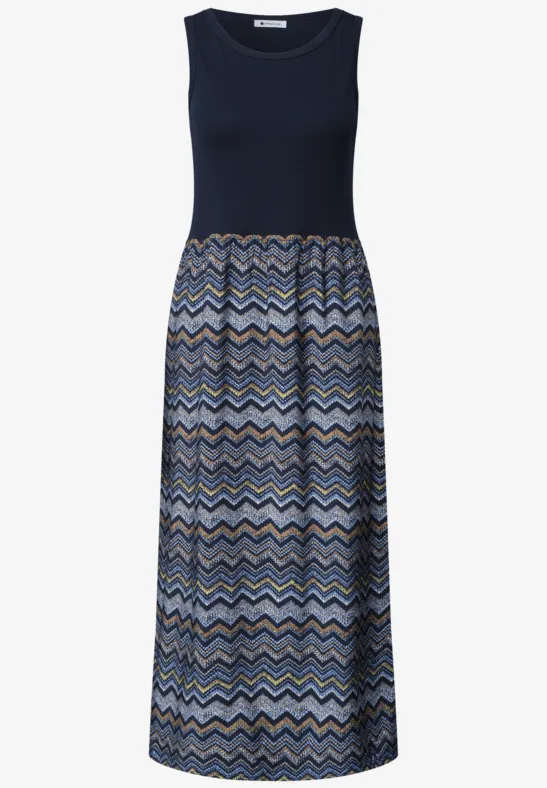 Mouwloze maxi-jurk met donkerblauwe top en zigzagpatroon in blauwtinten en beige.