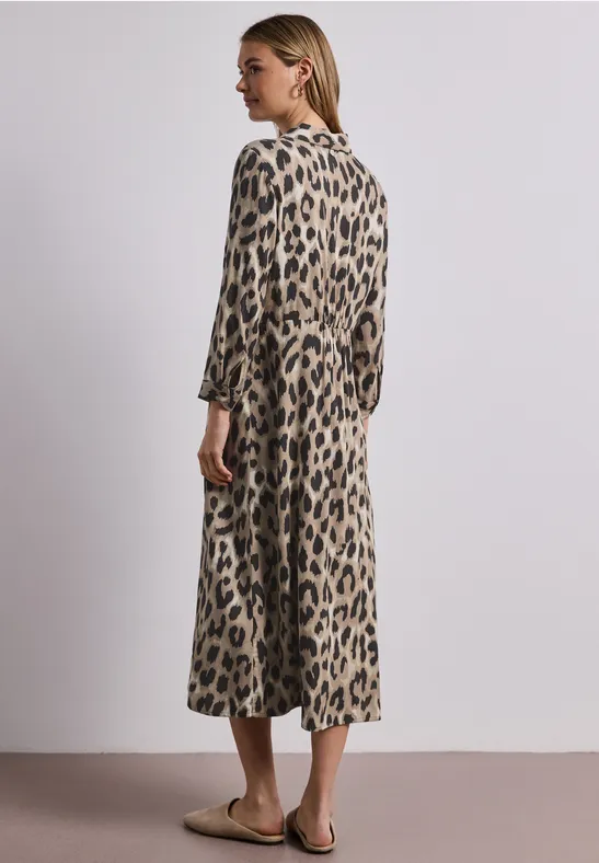 Frau in midi Längen Leopardenmuster-Kleid mit 3/4 Ärmeln, seitlich stehend auf neutralem Hintergrund