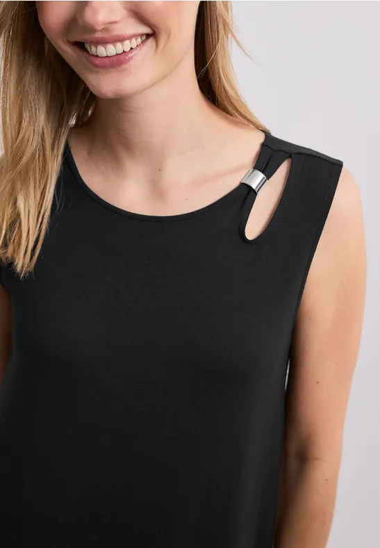 Vrouw in mouwloze zwarte top met kleine schouderuitsnijding en zilveren ring.