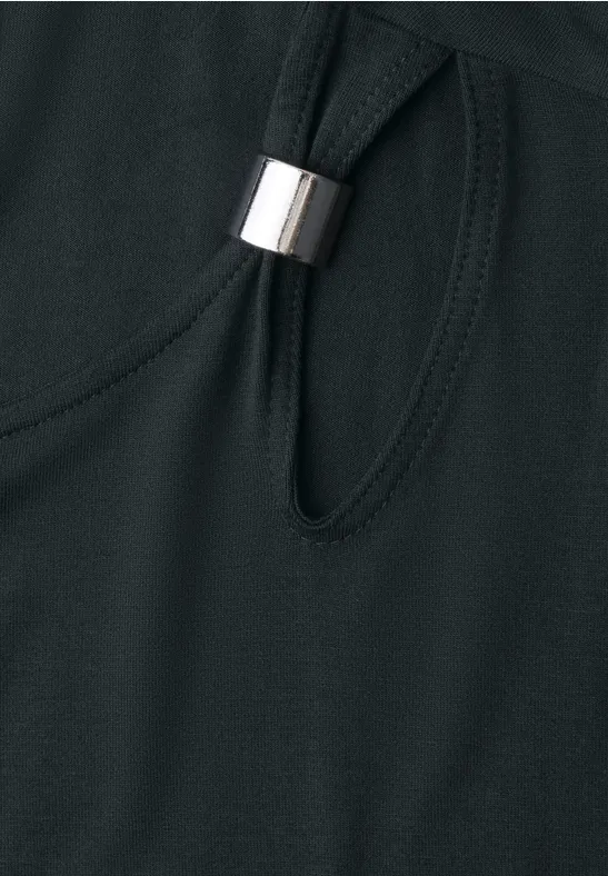 Gros plan sur un tissu noir avec une découpe ovale et un anneau métallique argenté.