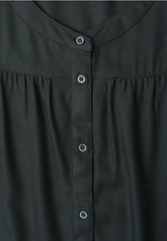 Zwarte blouse met ronde hals en centrale knoopsluiting.