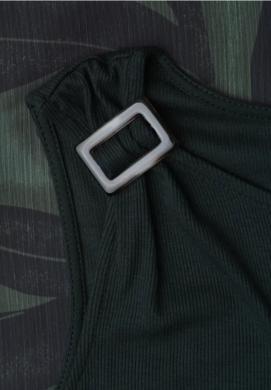 Close-up van een donkergroene stoffen band met een zilverkleurige rechthoekige gesp op camouflageachtergrond.