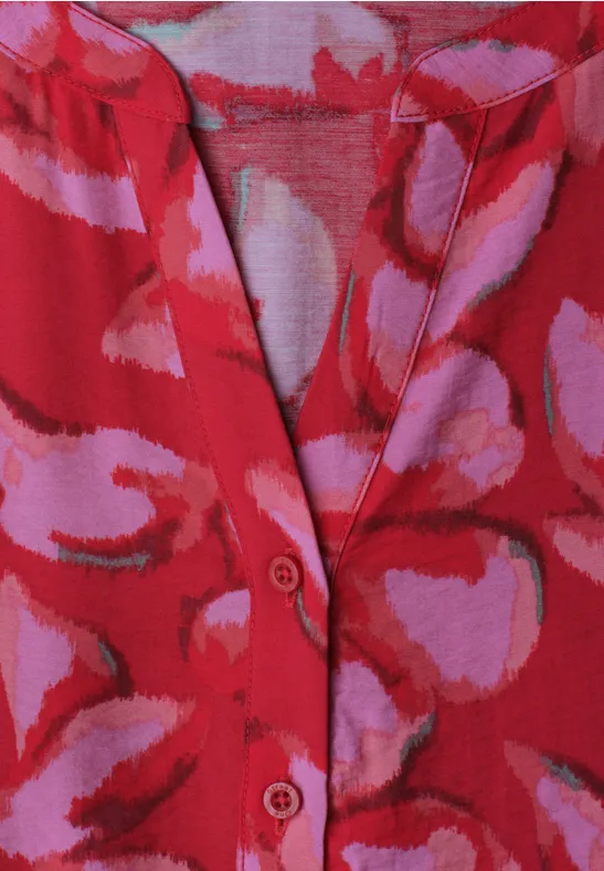 Rotes Strickoberteil mit rosa-lila abstrakten Mustern, V-Ausschnitt mit Knopfleiste.