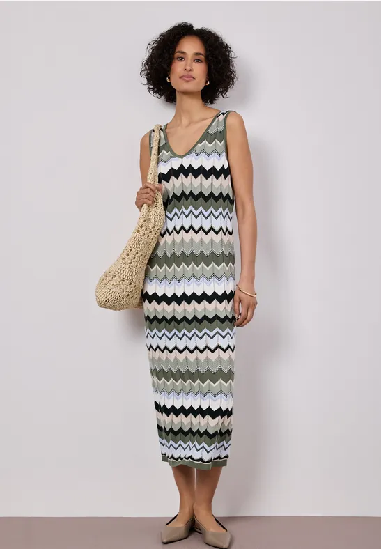 Frau trägt midilanges, ärmelloses, gestricktes Zigzag-Kleid und Korbtasche im sommerlichen Look.