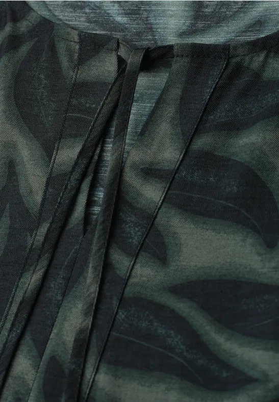 Close-up van een donkergroen camouflagepatroon met zwarte accenten en koorden