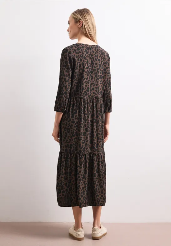 Vrouw van achteren in een bruin-zwart midi-jurk met luipaardprint en 3/4-mouwen.