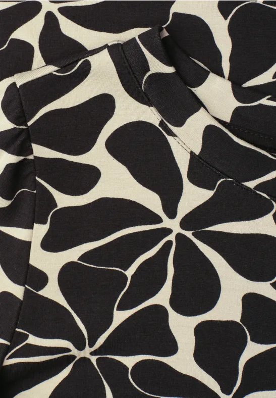 Abstract bloemmotief met zwarte, organische vormen op crèmekleurige stof