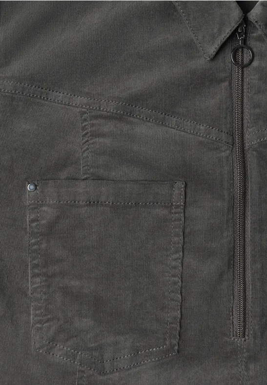 Chemise foncée avec poche poitrine, fermeture éclair verticale et détail de boucle métallique