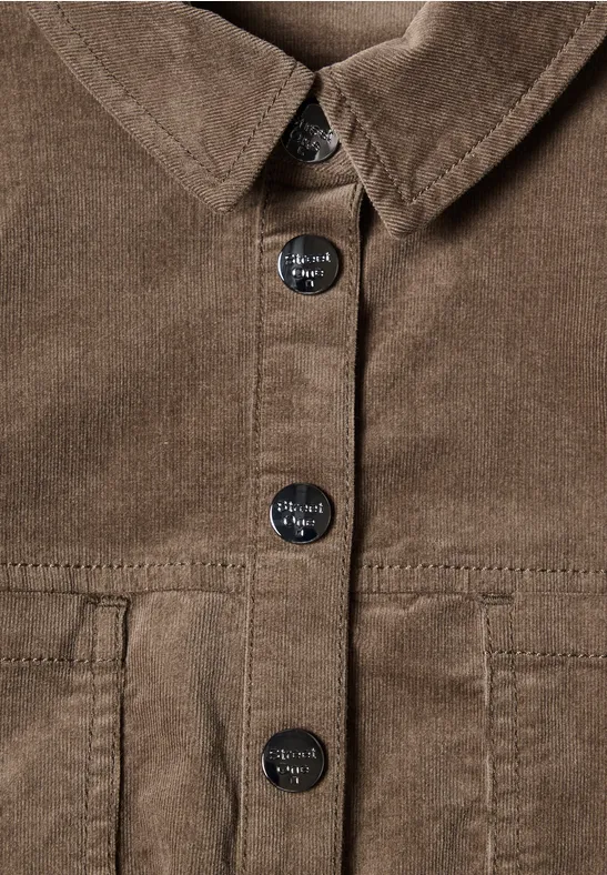 Nahaufnahme einer braunen Cordjacke mit Knopfleiste und aufgesetzten Taschen.