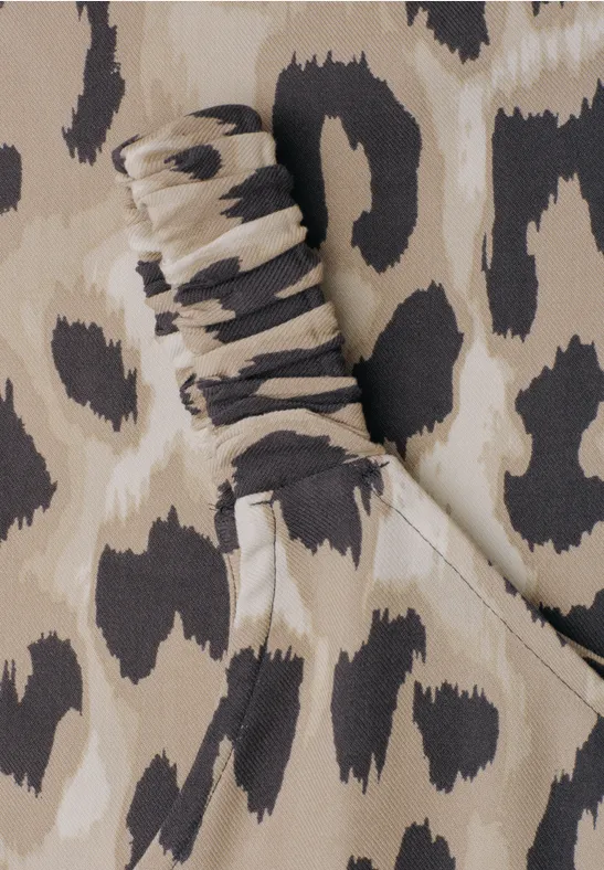 Beiger Leoprint mit dunkelbraunen und schwarzen Flecken, Detail einer gerafften Manschette und Schlitz