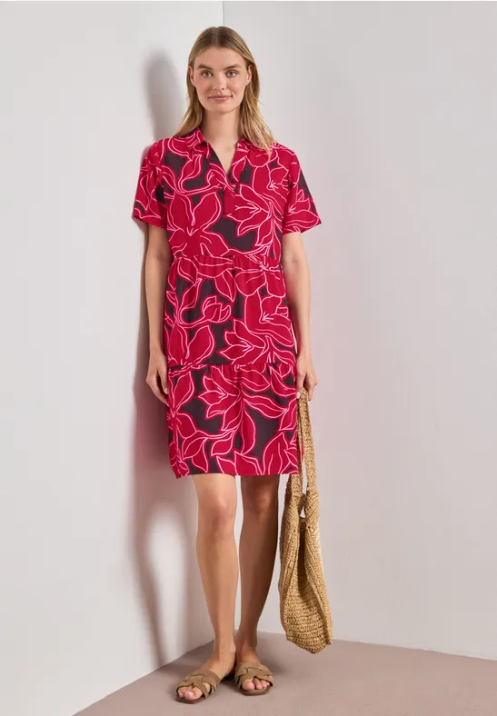 Vrouw in rode bloemenjurk met V-hals, korte mouwen, strozak en platte sandalen