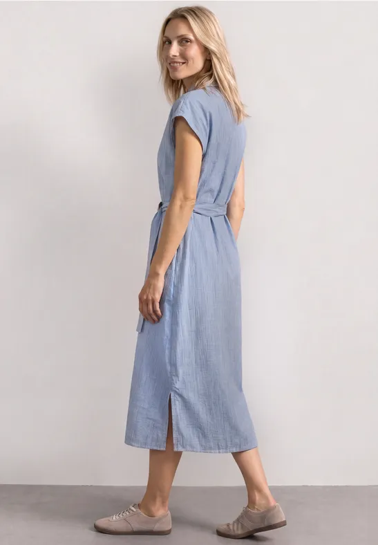 Frau im hellblauen Midi-Kleid mit kurzen Ärmeln, tailliertem Schnitt und seitlichem Schlitz.