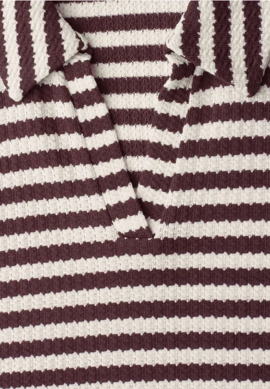 Close-up van een grof gebreid poloshirt in bordeauxrood en wit met kraag en V-hals.