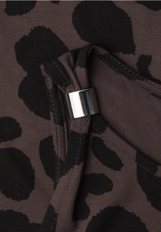 Tissu marron à motifs léopard noirs et boucle métallique argentée en gros plan.