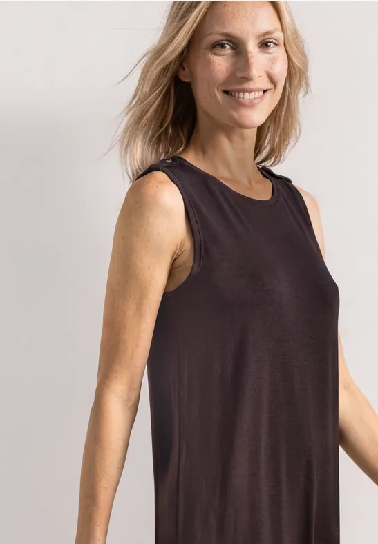 Femme de profil vêtue d’un débardeur noir, fond clair.