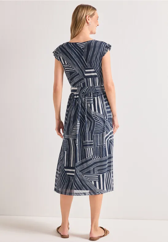 Vrouw van achteren in marineblauwe midi-jurk met geometrisch dessin en ceintuur