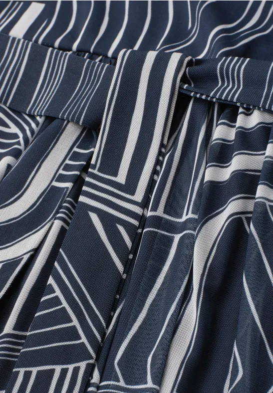 Donkerblauw stof met witte geometrische strepen en subtiele plooien.