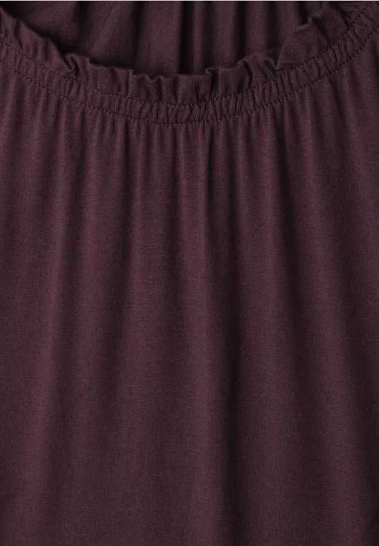 Haut féminin grenat avec encolure ronde froncée et bande élastique.