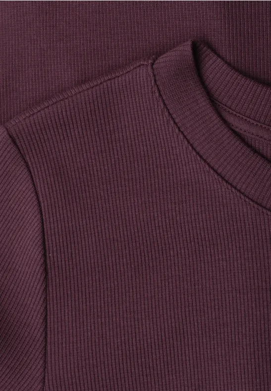 Close-up van een dieprood, geribd gebreid bovenstuk met ronde hals.