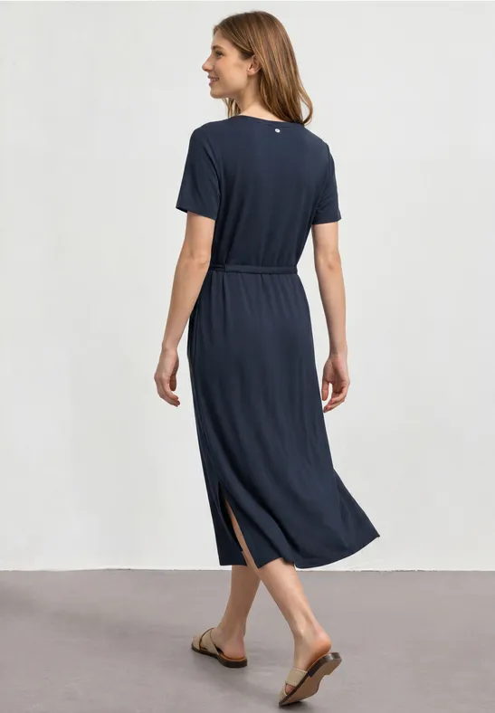 Femme de dos portant une robe midi bleu marine à manches courtes, ceinture à la taille et sandales.