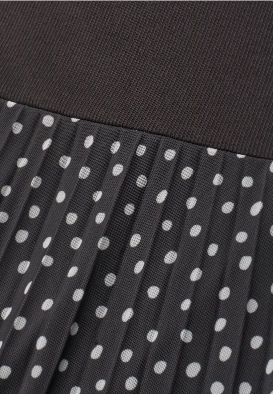 Tissu noir côtelé sur jupe plissée à pois blancs