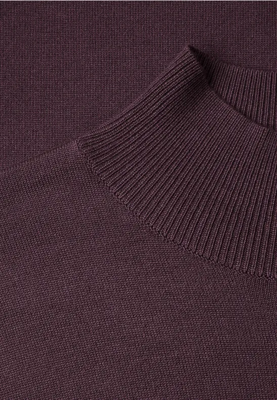 Gros plan d'un pull à col roulé tricoté de couleur violet foncé.