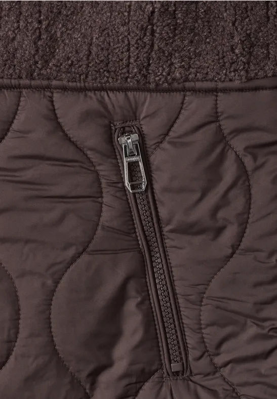 Poche zippée sur une veste matelassée brune, avec un tissu supérieur texturé.