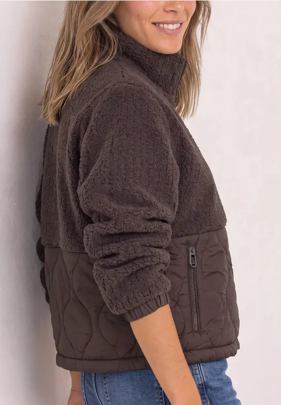 Femme portant une veste marron en sherpa et matelassée, vue de côté, souriante