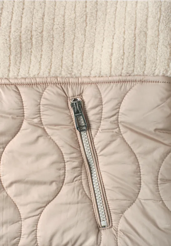 Gros plan sur un tissu matelassé beige clair avec fermeture éclair et tricot texturé en haut.