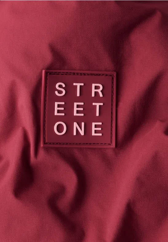 Tissu bordeaux avec un patch rectangulaire marqué 'STREET ONE'.