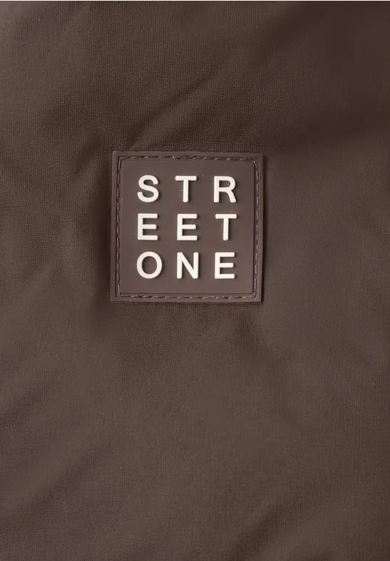 Brauner Stoff mit eingenähtem braunen Patch und weißem STREET ONE-Logo in Blockschrift.
