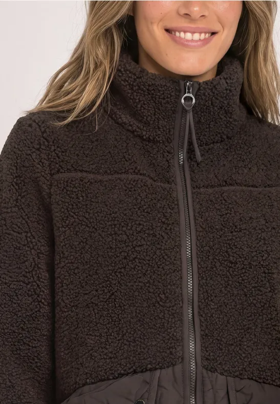 Nahaufnahme einer Person in brauner Fleecejacke mit Reißverschluss und hohem Stehkragen.