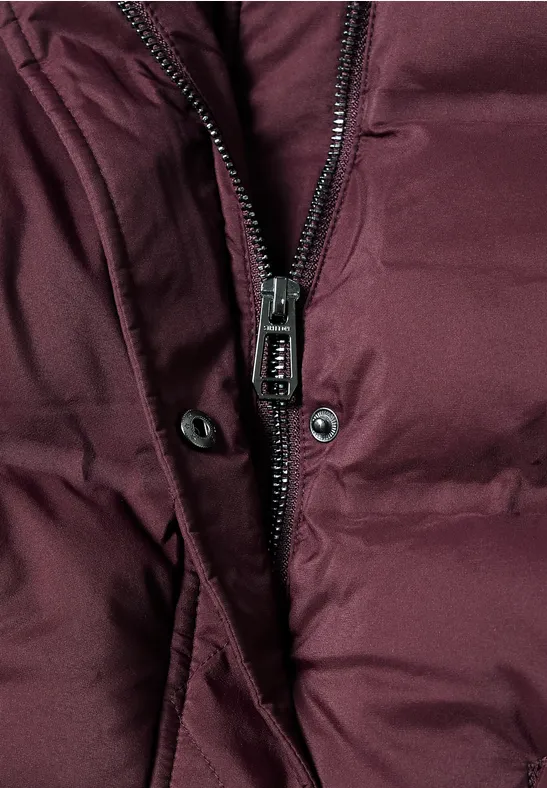 Nahaufnahme einer dunkelroten gesteppte Jacke mit Reißverschluss und Druckknöpfen.