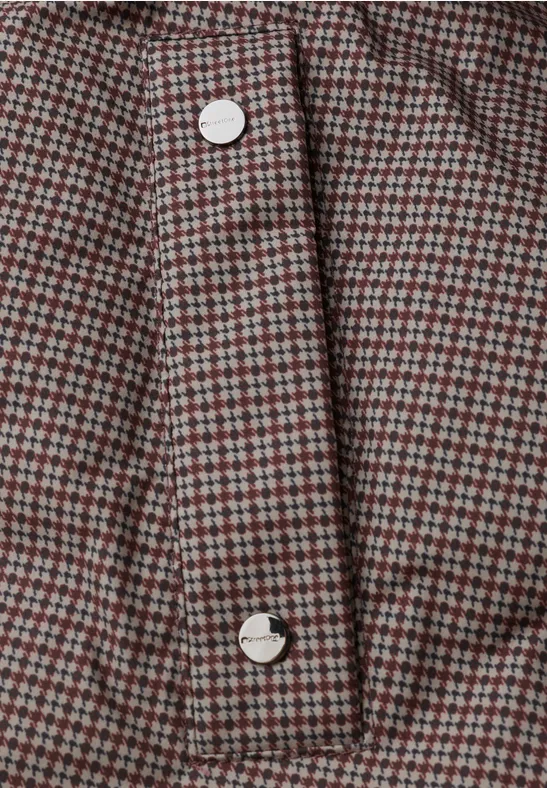 Nahaufnahme eines rot-grau karierten Stoffes mit weißen Knöpfen an einer Knopfleiste.