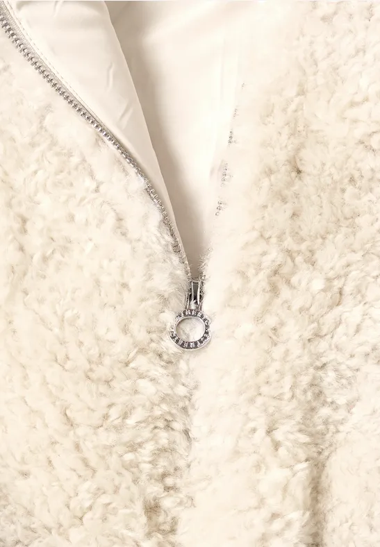Witte teddy-achtige fleece met ritssluiting en zilveren ringtrekker op zacht materiaal.