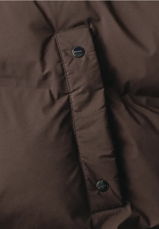 Gros plan d'une doudoune marron avec boutons-pression.