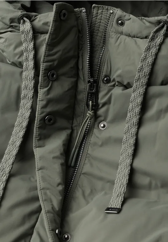 Nahaufnahme einer olivgrünen Steppjacke mit Reißverschluss und geflochtenen Zugbändern