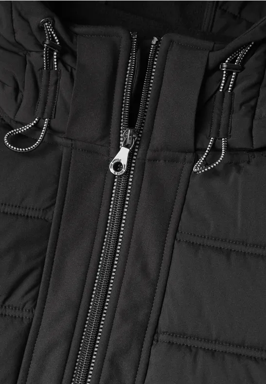 Vue rapprochée d'une veste matelassée noire avec fermeture éclair centrale et cordons.