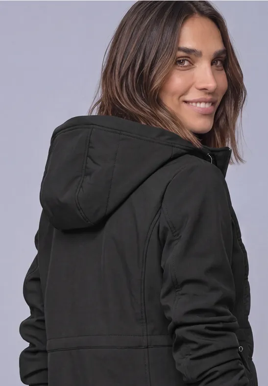 Une femme en sweat à capuche noir regarde en souriant par-dessus son épaule.