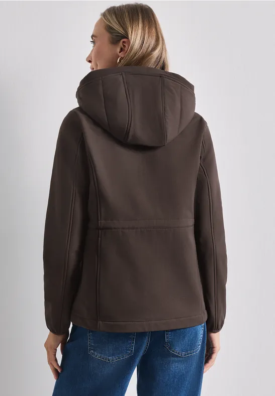 Femme vue de dos portant une veste à capuche marron et un jean bleu.