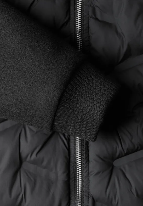 Veste noire matelassée avec fermeture éclair et bord-côte élastique à la manche.
