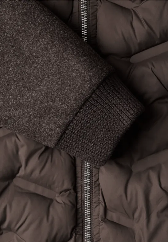 Gros plan d’un manteau matelassé gris foncé avec une fermeture éclair et un poignet en maille.