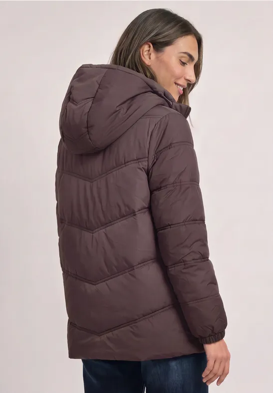 Femme portant une doudoune marron à capuche, vue de dos et de profil.