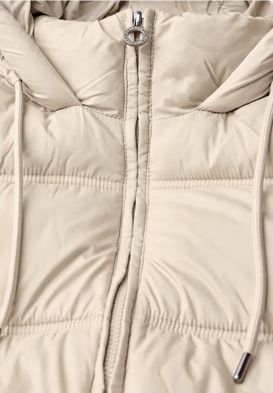Helle Daunenjacke in Creme mit Reißverschluss, Ring-Zipper und Kordelzug am Kapuzenbereich.